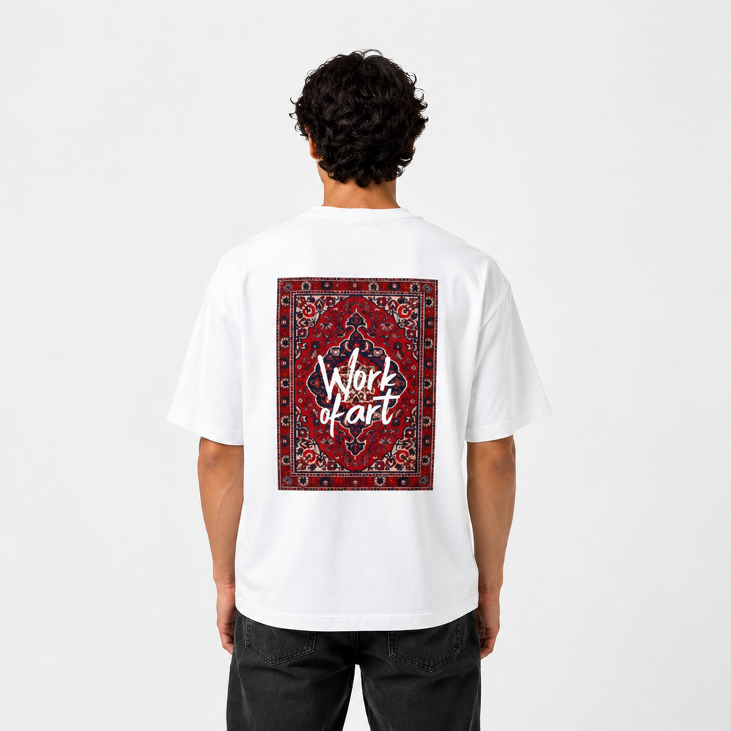 A man viewed from behind wearing a white t-shirt with a large red and black patterned graphic on the back featuring the text 'Work of art' in white script, paired with black jeans against a light gray background.