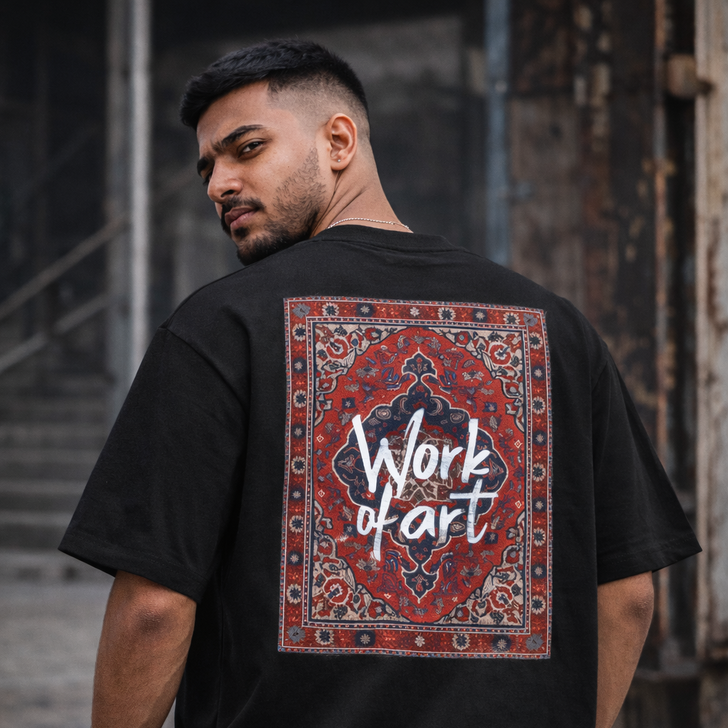 Man wearing a black t-shirt with a colorful design and 'Work of Art' text on the back, standing against an urban background.